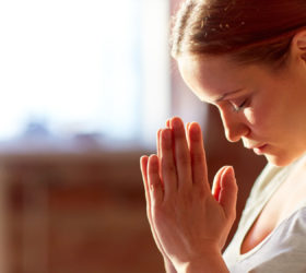 religion, faith and people concept - close up of woman meditating at yoga studio